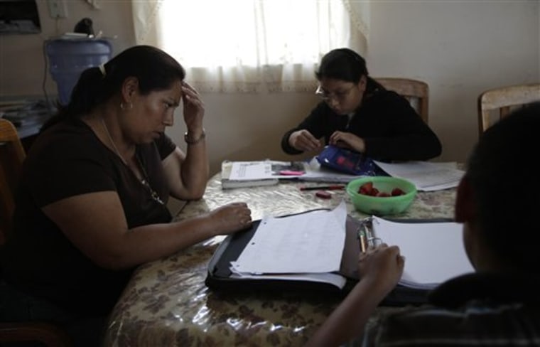Domitila Lara, left, helps her children Ariana, center, and Eduardo, right, with their homework in San Diego. Lara, 44, waited for months to receive food stamps after her husband lost his job in construction. 